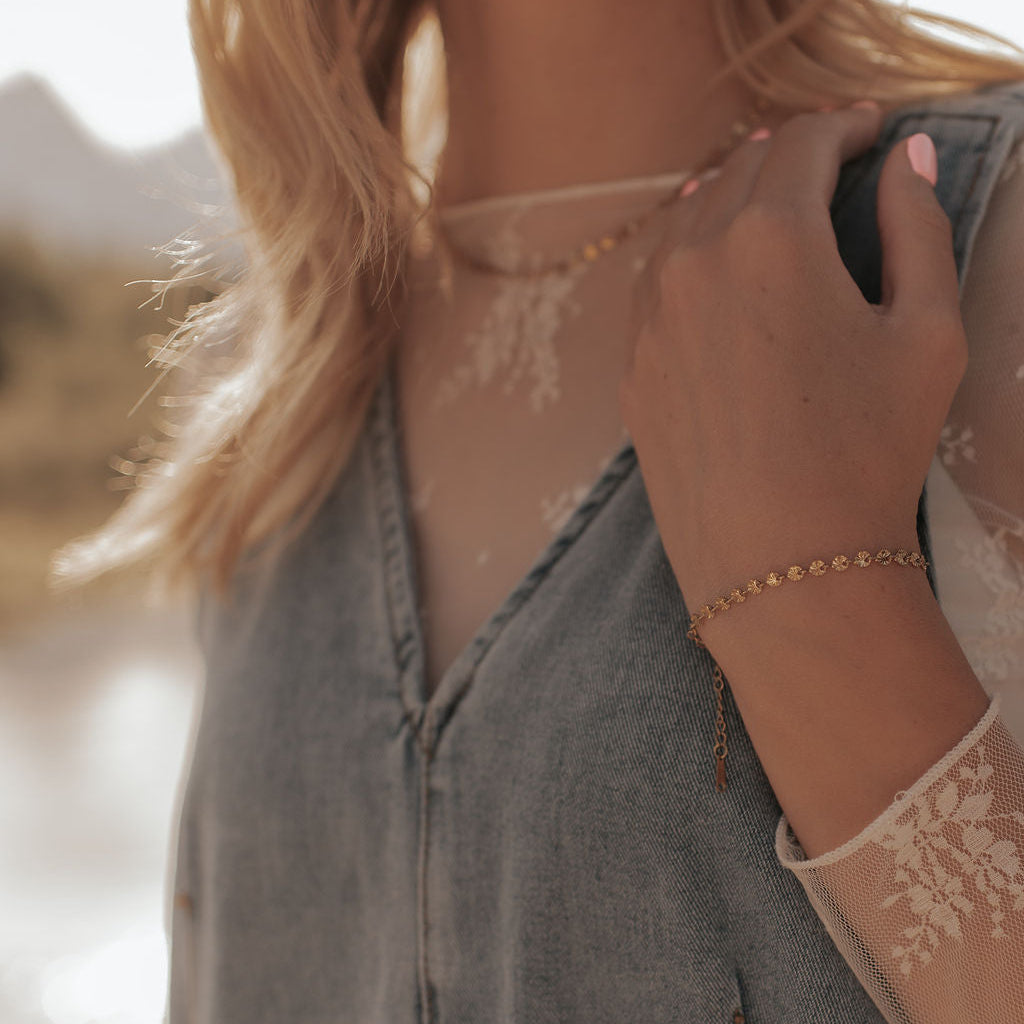 Person wearing a denim jacket with lace sleeves against a blurred natural background