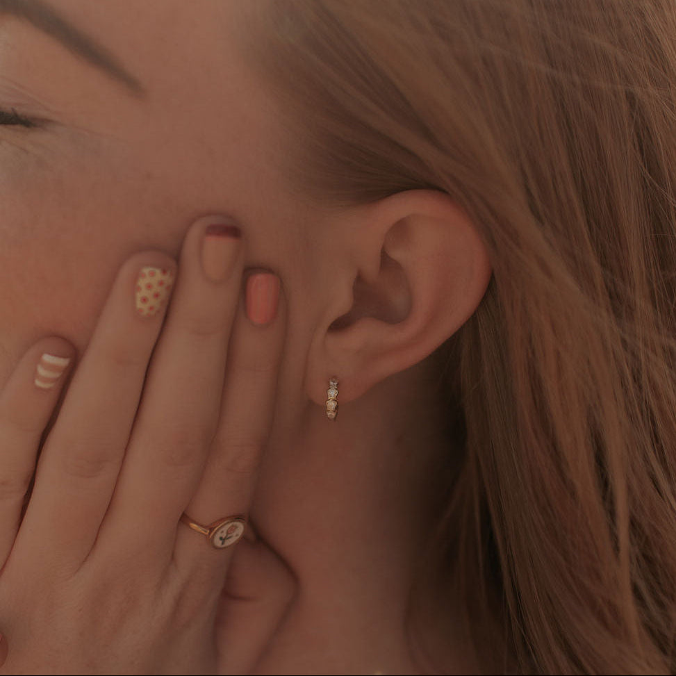 Close-up of a person wearing gold earrings and rings with a blurred background