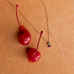 Load image into Gallery viewer, Two red cherries on a gold chain against a beige background

