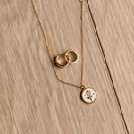 Gold necklace with circular pendants on a wooden surface