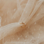 Gold ear cuff with a diamond on beige fabric