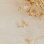 Gold earrings with pearls on a textured beige surface with flowers