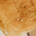 Close-up of a yellow cloth with two small pearl earrings on top