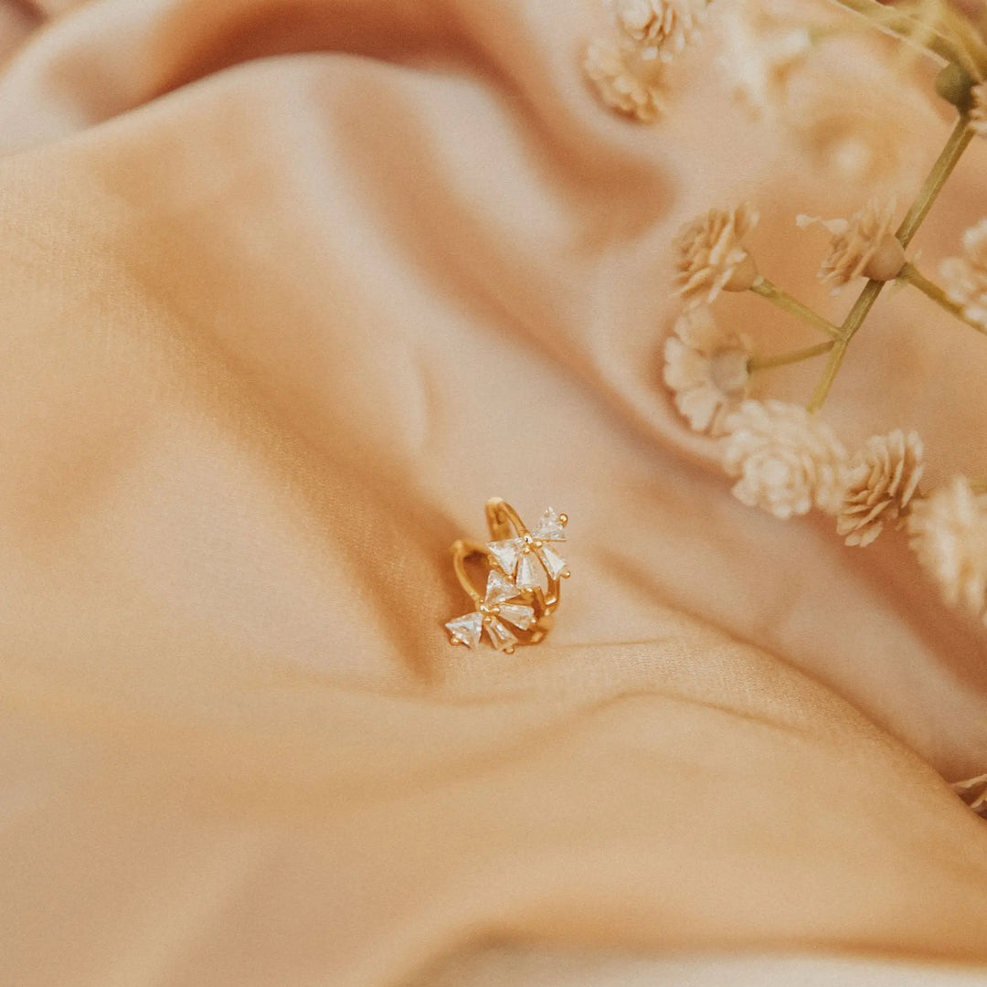 Gold earring with a soft beige background