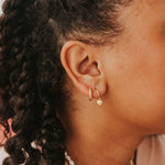 Close-up of an ear wearing gold hoop earrings with a soft focus on hair and skin.
