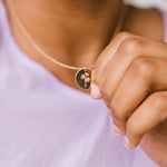 Load image into Gallery viewer, Close-up of a necklace with a pendant held by a hand against a blurred background
